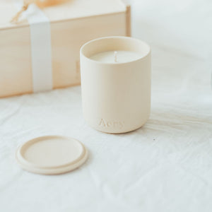 white ceramic soy candle gift on a white linen tablecloth with a wooden keepsake gift box