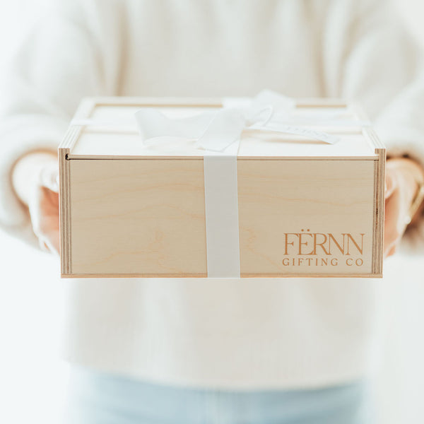 fernn gifting co branded wooden keepsake gift box gift wrapped in white grosgrain ribbon on white linen tablecloth