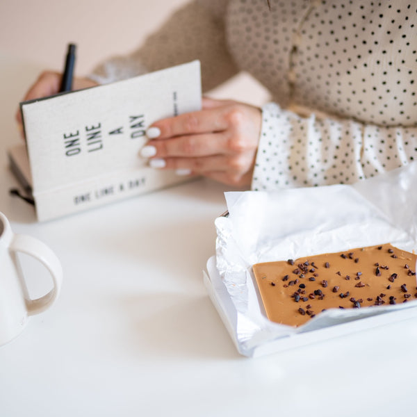 woman writing in one line a day with white chocolate bar gift