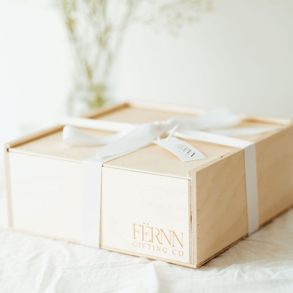fernn gifting co branded wooden keepsake gift box gift wrapped in white grosgrain ribbon on white linen tablecloth